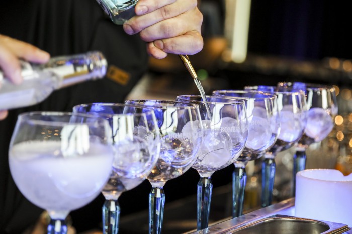 Ein Cocktail wird im House of Gin im Hotel Palace Berlin zubereitet. Ein Barkeeper gießt die Zutaten ein, während das Glas stilvoll angerichtet wird.