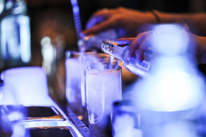 Ein Cocktail wird im House of Gin im Hotel Palace Berlin zubereitet. Ein Barkeeper gießt die Zutaten ein, während das Glas stilvoll angerichtet wird.