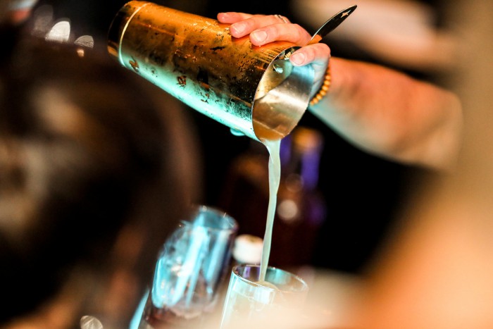 Ein Cocktail wird im House of Gin im Hotel Palace Berlin zubereitet. Ein Barkeeper gießt die Zutaten ein, während das Glas stilvoll angerichtet wird.
