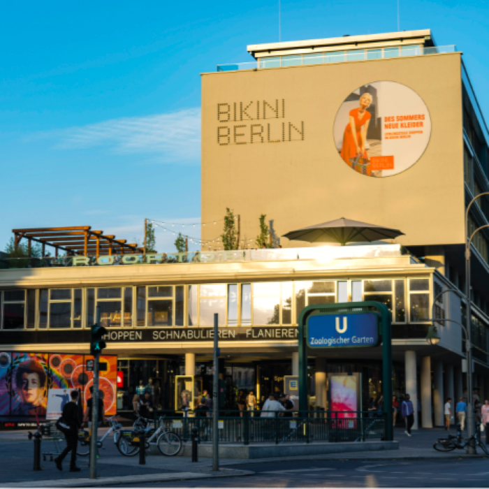 Die Bikini Berlin Mall unter strahlend blauem Himmel, mit moderner Architektur und lebendiger Einkaufsatmosphäre.