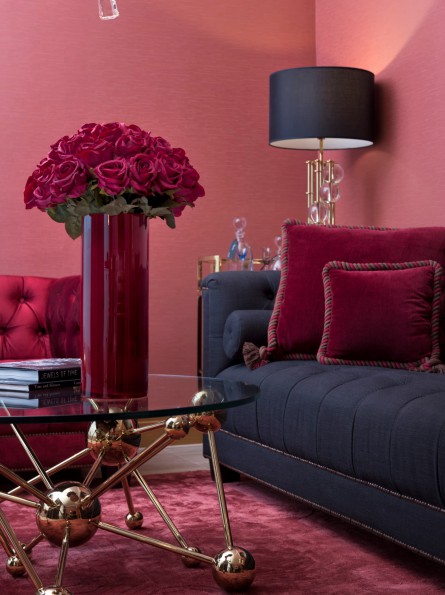 Elegant hotel Corner Suite  living room in Hotel Palace Berlin in central Berlin with modern chandelier, velvet sofas, glass coffee table, and a large portrait on the wall, featuring floor lamps and refined glass accents.