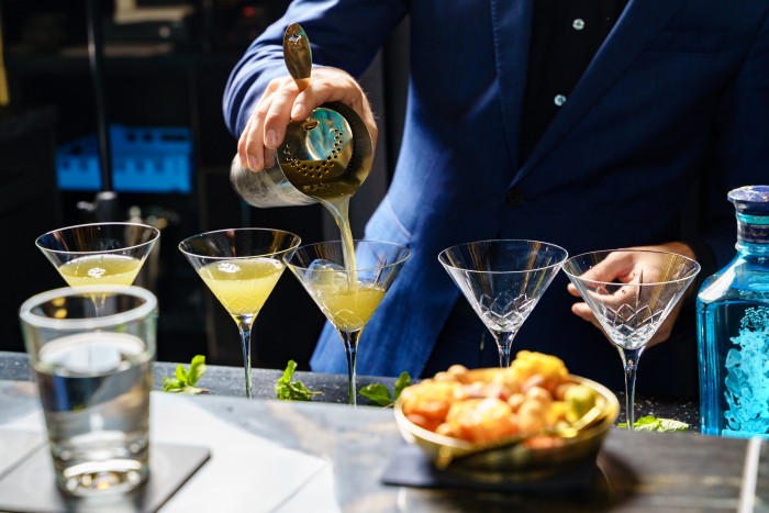 Ein Cocktail wird im House of Gin im Hotel Palace Berlin zubereitet. Ein Barkeeper gießt die Zutaten ein, während das Glas stilvoll angerichtet wird.