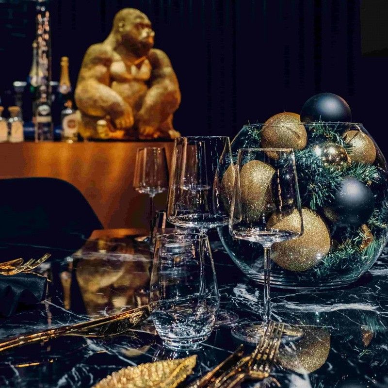 Luxuriöser Weihnachtstisch im Restaurants beef45 mit gedimmtem Licht, dunklen Wänden und grünen Samtstühlen an schwarzen Marmortischen. Einzigartige Leuchten und eine Wandgestaltung mit roten und blauen Linien verstärken die elegante Atmosphäre.